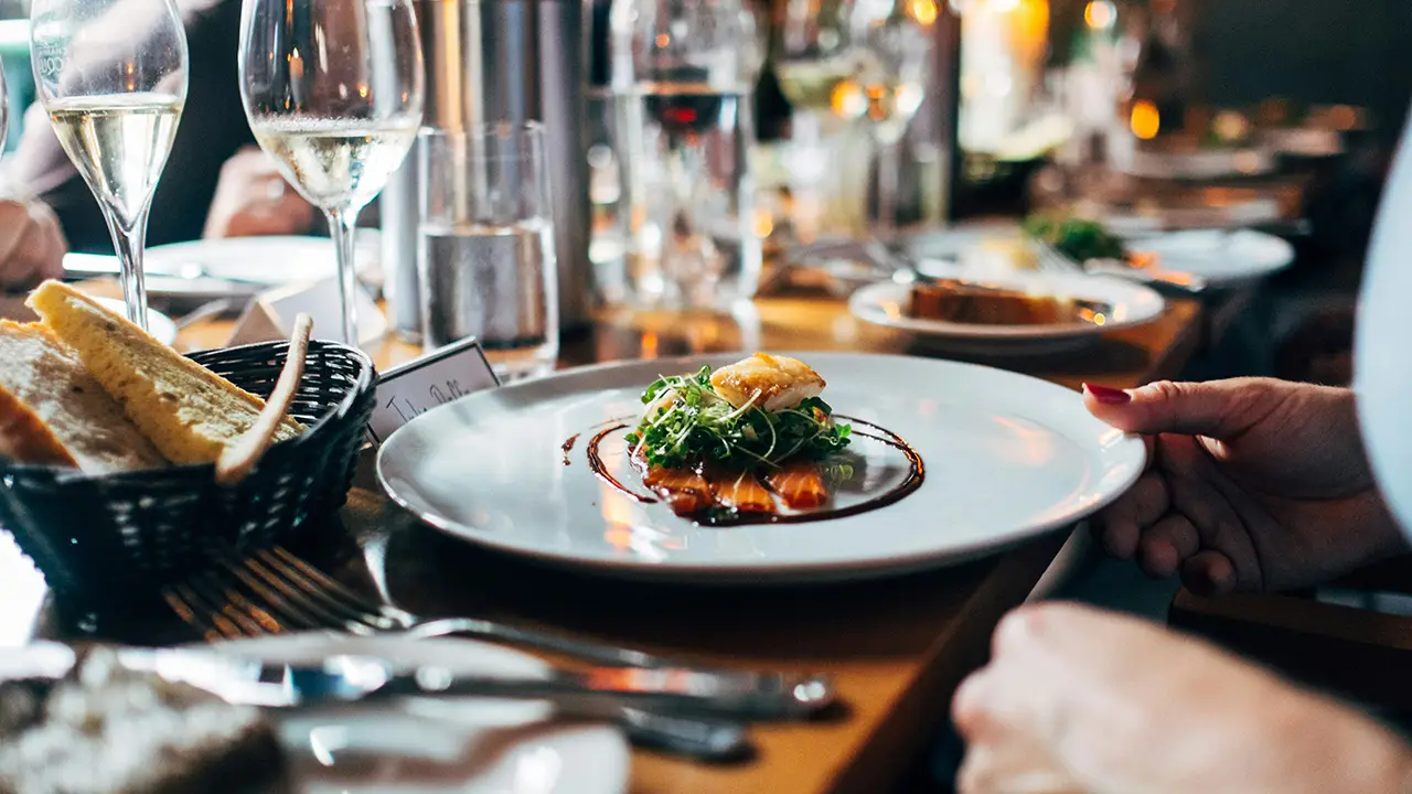 Restaurant Website erstellen: stilvoll angerichtetes Gericht mit Brot und Wein im Restaurant